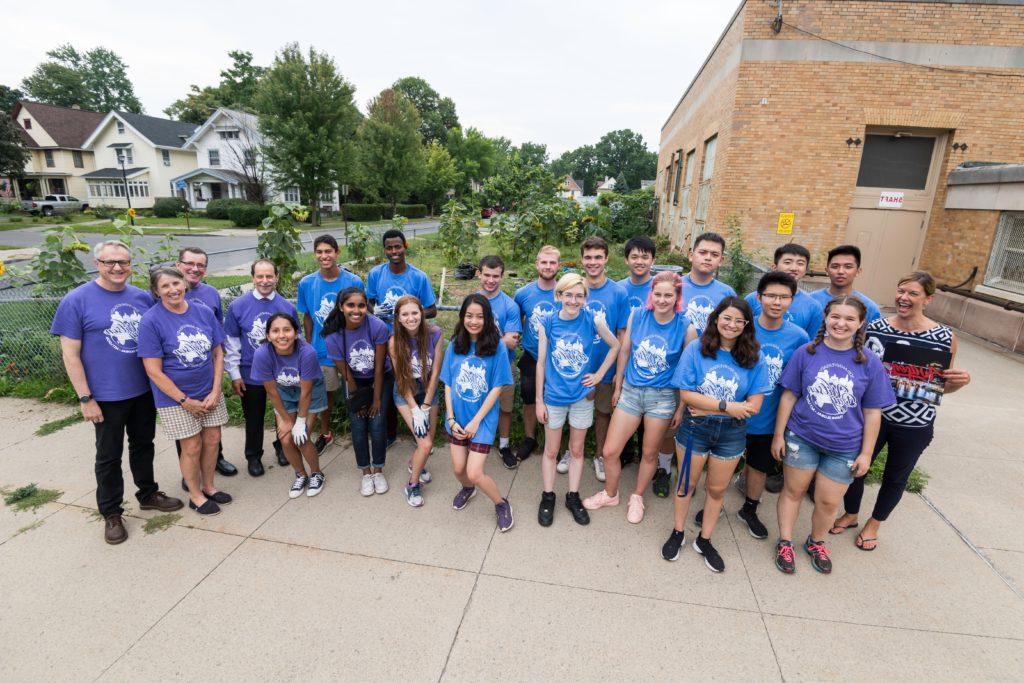 students pose for a photo next to the community garden at Wilson Magnet High School with Wilson and UR leadership