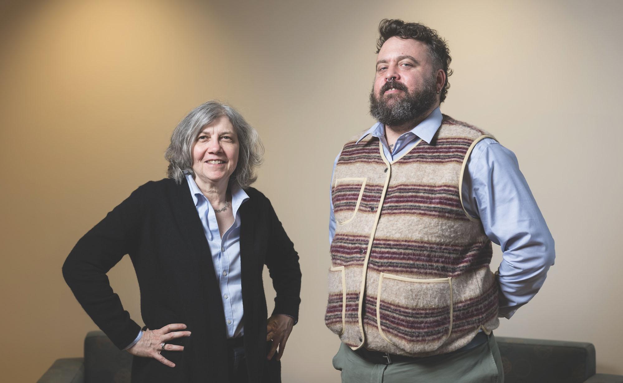 Peter Christensen and Lainie Ross standing next to each other against lit wall.