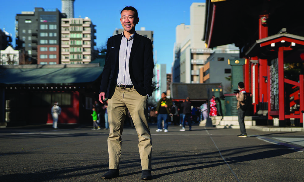 Yohay Wakabayashi in khakis and suit jacket standing in busy Tokyo plaza.